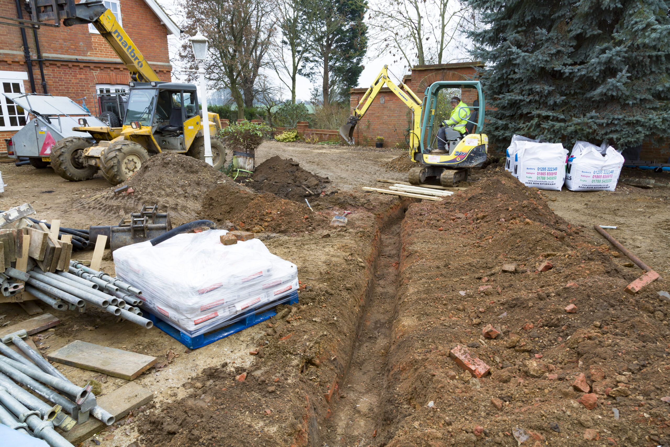 Buckingham, UK - December 02, 2016. Digger driver, digging a trench for drains on a UK building site